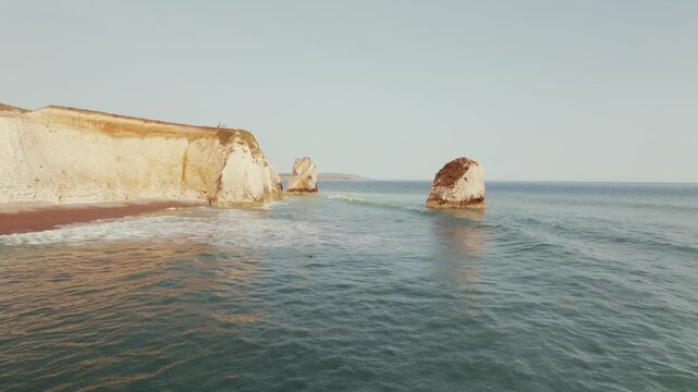 Turquoise sea waves rolling towards chalk cliffs at Freshwater Bay