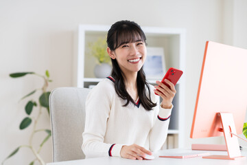 オフィスでスマホを使う若い女性 © pain au chocolat