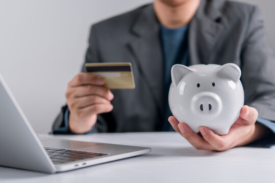 Businessman holding credit card and piggy bank using laptop online savings