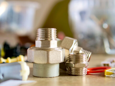 Plumbing brass union fitting and threaded pipe connectors close up on workshop table; conceptual for home plumbing repair, diy hardware maintenance, renovation construction and engineering