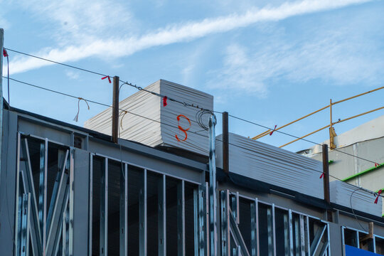 Building under construction with metal framing and stacked insulation panels against a bright blue sky, showcasing urban development and ongoing work in the construction industry.