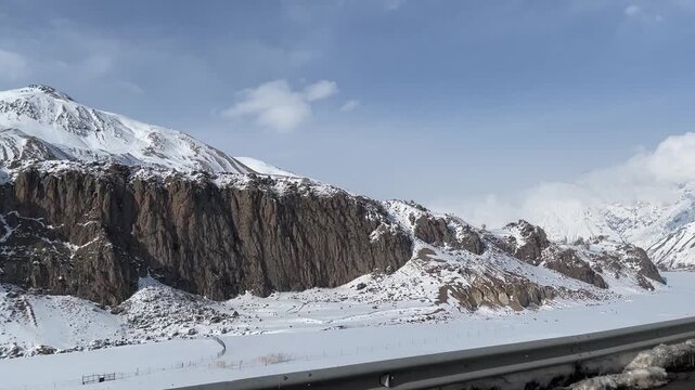 Scenic point of view footage from a moving car window capturing majestic snowy Caucasus mountains along the winter highway road in Stepantsminda region of Georgia. High quality FullHD footage