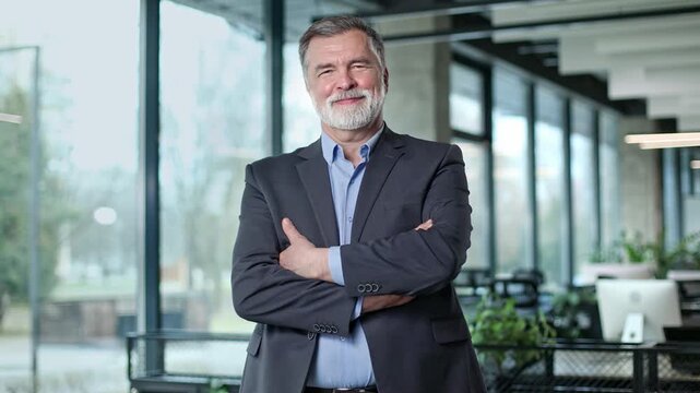 Confident man stands with crossed arms in modern office