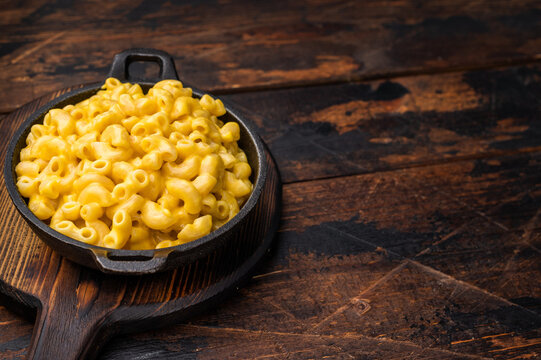 Savory mac and cheese in skillet on dark wood &mdash; cozy food photo for menus.