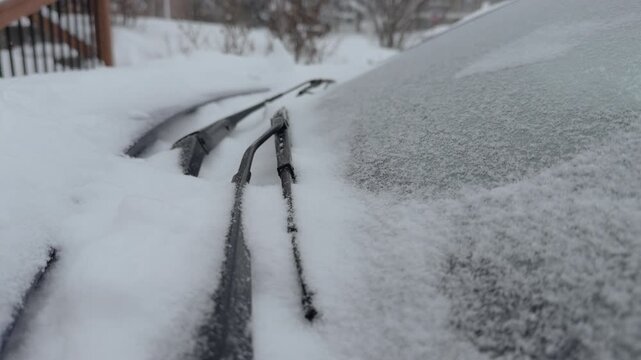 Frozen wiper blades on window with snow falling 4k