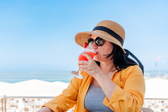Lonely woman drinking cocktail alone at an all inclusive beach resort. Emotional burnout, escapism, solo vacation and unhealthy coping habits concept during summer holidays.