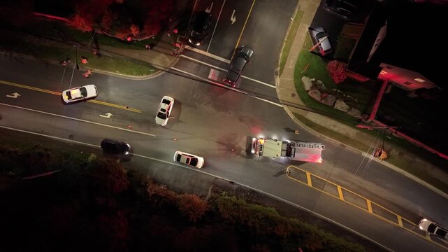 An aerial view shows a car collision in Beechville, Canada. Emergency services respond as onlookers watch from the sidewalk. Damage is evident with a tow truck on the scene