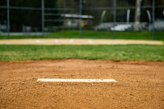 Ground-level view of the infield of a baseball field with the empty white plate on the pitcher's mound stretching out horizontally across the foreground of the shot.