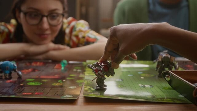 Young woman in glasses resting her head on her hands and observing her friend making move while playing RPG tabletop game