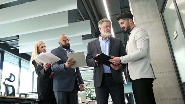Four professionals collaborate in a bright, modern office space