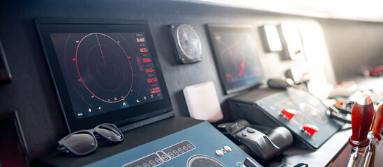 Digital dashboard with navigation monitor system, marine radar, VHF Radio and binoculars in ship captain bridge. Wheelhouse steering console on Nautical vessel transport. Modern boating technology © zephyr_p