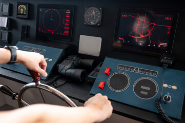 Captain hand holding steering wheel while controlling dashboard. GPS navigation map and marine radar monitor for modern boating technology. Nautical vessel control panel in wheelhouse or ship bridge © zephyr_p