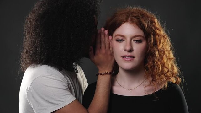 Intimate relationship and connection. A diverse couple shares a tender moment, with a man whispering gently into a woman s ear in a close up studio shot. This footage is projects focusing on love, rom