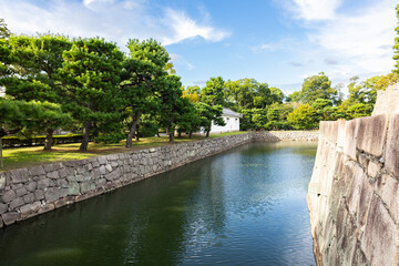 Fototapeta premium Panoramic canal view at Nijo Castle Kyoto featuring defensive moat traditional landscape and cloudy sky, Kyoto, Japan 