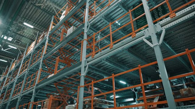 Expansive industrial warehouse interior with towering steel pallet racks, orange safety railings, and stacked cargo under bright overhead lighting in a logistics storage facility