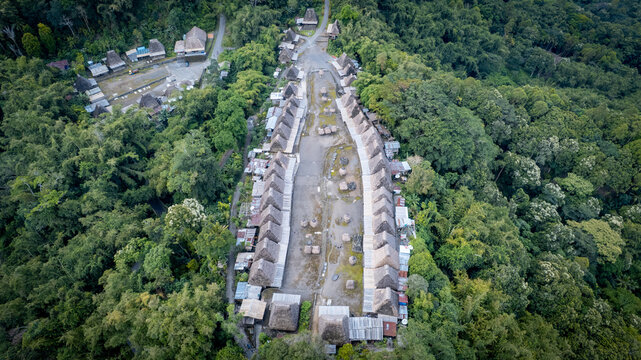 Aerial view of Bena Traditional Village featuring rows of thatched-roof houses surrounded by dense tropical forest in Kecamatan Jerebuu, Nusa Tenggara Timur, Indonesia.