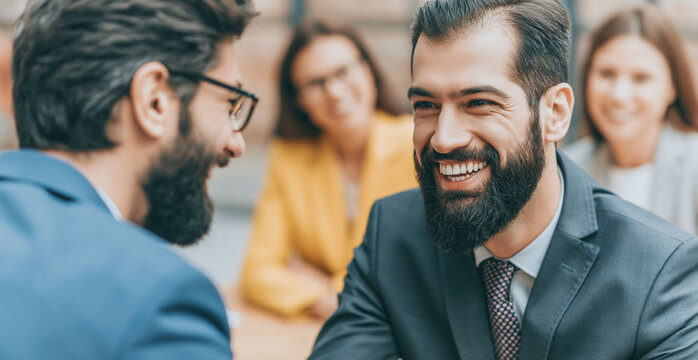 Corporate team members exchanging handshakes and conversation around a conference communication, career success and relationships.