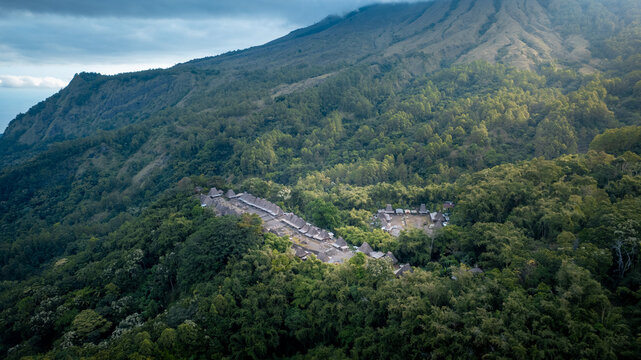 Aerial view of Bena Traditional Village with thatched roof houses nestled in a dense tropical forest on a mountain slope in Kecamatan Jerebuu, Nusa Tenggara Timur, Indonesia.