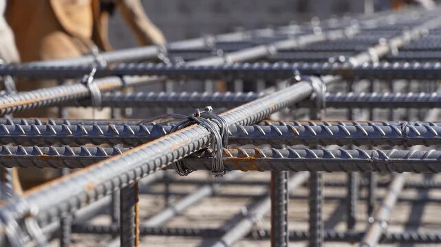 Construction workers meticulously tying steel reinforcing bars for a building foundation, ensuring structural integrity and durability.