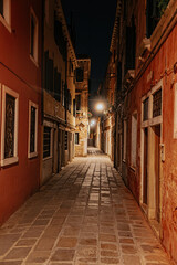 Fototapeta premium Empty Venice street at night with soft lights and historic architecture