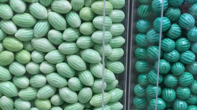 Close-up of colorful candies in transparent containers on a store display, showing a variety of bright sweets in different shapes and colors.
