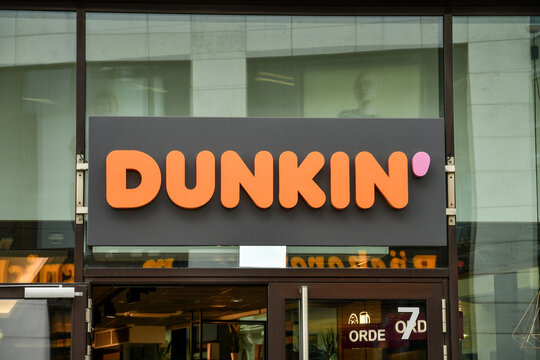 Close-up of the Dunkin' brand logo sign above the storefront entrance of a coffee and donut shop