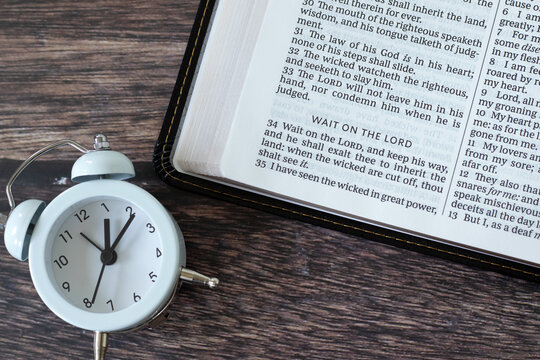 Wait on the LORD, christian encouragement text in holy bible with alarm clock. Patience and faith in God Jesus Christ, biblical concept. Top view.