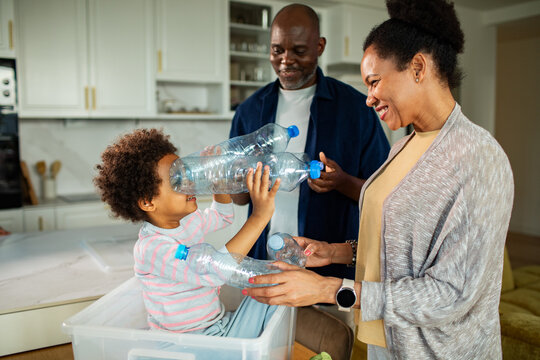 Parents and child recycling plastic bottles in home kitchen