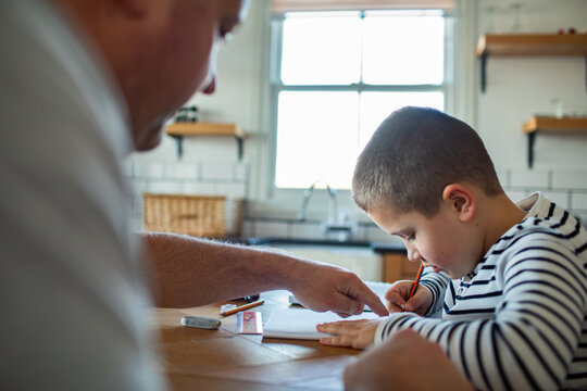 Parent helping child with homework at kitchen table