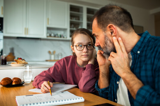 Parent teaching teen sign language during homework in kitchen