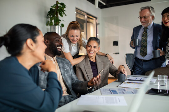 Diverse business team laughing together in office meeting