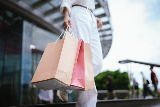 Close-up of a shopper carrying colorful shopping bags outdoors, symbolizing retail spending, consumer lifestyle, fashion purchases, and modern shopping experiences.