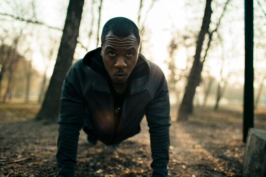 Focused man doing push-ups in a foggy park at sunrise
