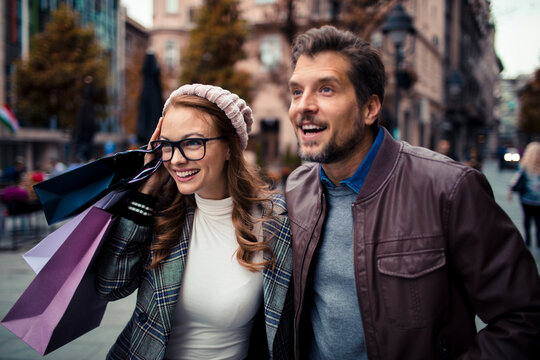 Happy couple shopping with bags on autumn city street
