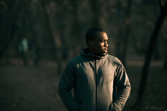 Athletic man in hoodie looking aside in forest park