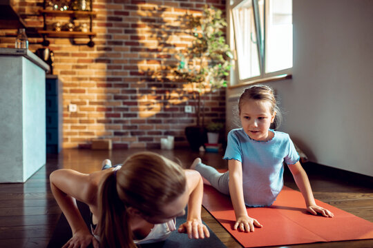 Mother and daughter practicing yoga at home