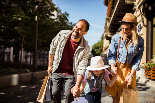 Parents and daughter shopping on sunny city street