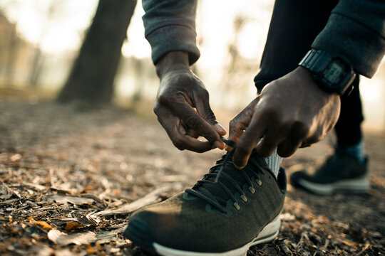 Runner tying shoelaces on forest trail at sunrise