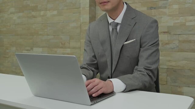 オフィスでパソコン作業をするスーツを着た日本人男性