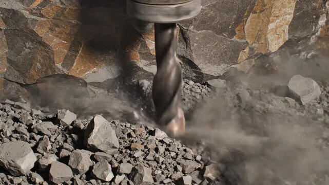 Powerful pneumatic drill bores into rock, creating dust and debris in an industrial excavation process