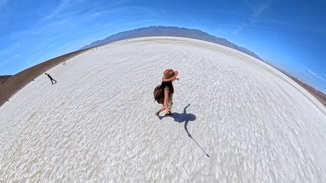 Young female traveler walking in the arid landscape of Death Valley National Park on a sunny day