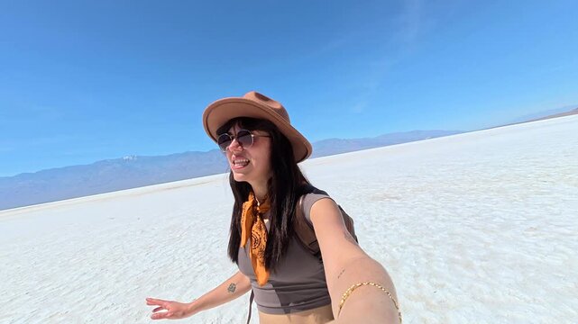 Young woman vlogging her solo travel adventure across the Badwater Basin salt flats in California