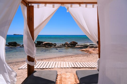 Rhodes island vacation in Greece. Navarone Bay beach canopy sunbeds in sunny weather in Lindos.