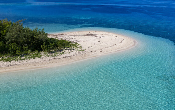 Aerial view of the pristine white sand beach of Yasawa Island with turquoise coral reefs and lush tropical vegetation under bright sunlight in Nadi, Western Division, Fiji.