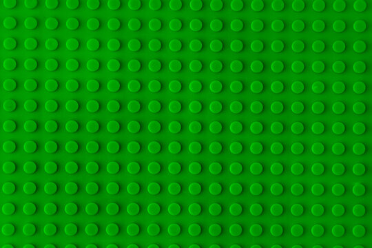Green plastic plate building blocks baseplate texture, top view toy brick board pattern construction background.