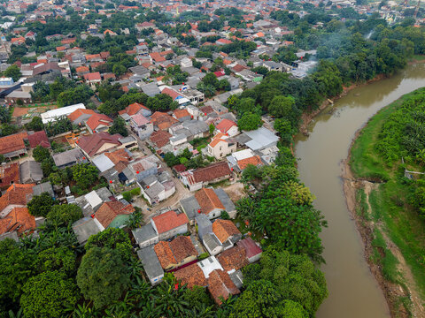 Aerial view of Kali Bekasi river flowing next to a crowded residential area in Indonesia