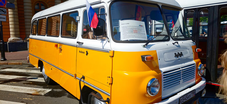 Saint Petersburg, Russia - May 23, 2026: Vintage Soviet-era yellow bus parked on city street with Russian flag and informational sign visible on the windshield