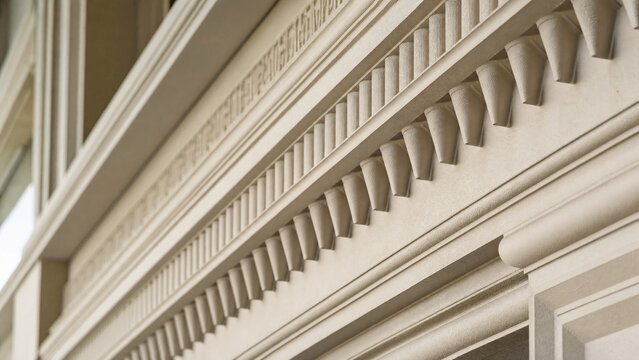 entablature. Classical architecture cornice featuring conical guttae details under soft window light. real-estate listings.