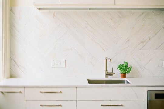 Modern Kitchen with Marble Backsplash and Brass Faucet