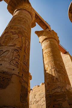 Epic Karnak temple ancient Egyptian architecture hypostyle hall panorama. 
Cinematic low angle view of historic Luxor sandstone columns, 
carved pharaoh hieroglyphs bas relief and blue sky.
